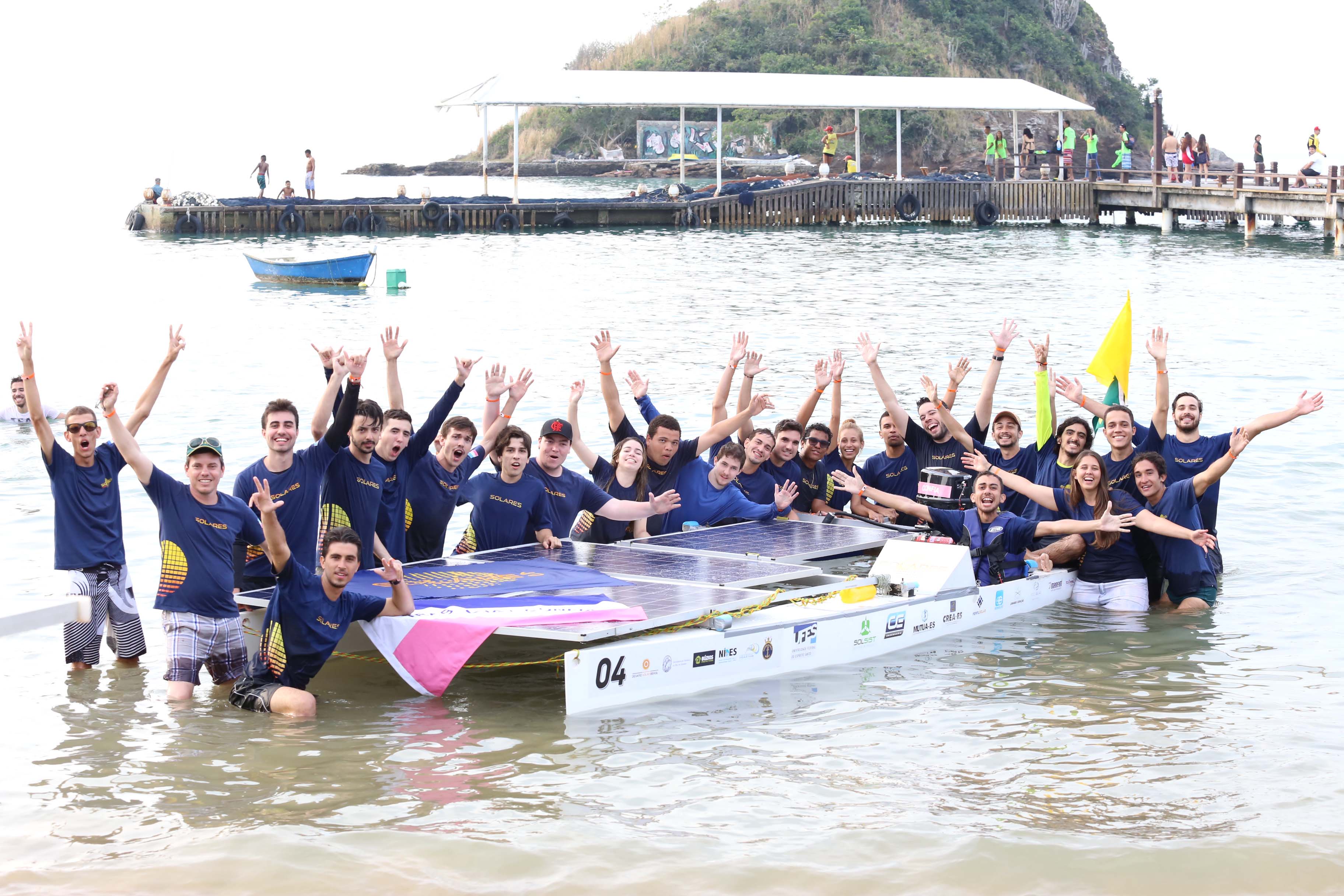 Estudantes comemoram vitória junto ao barco da competição, no mar